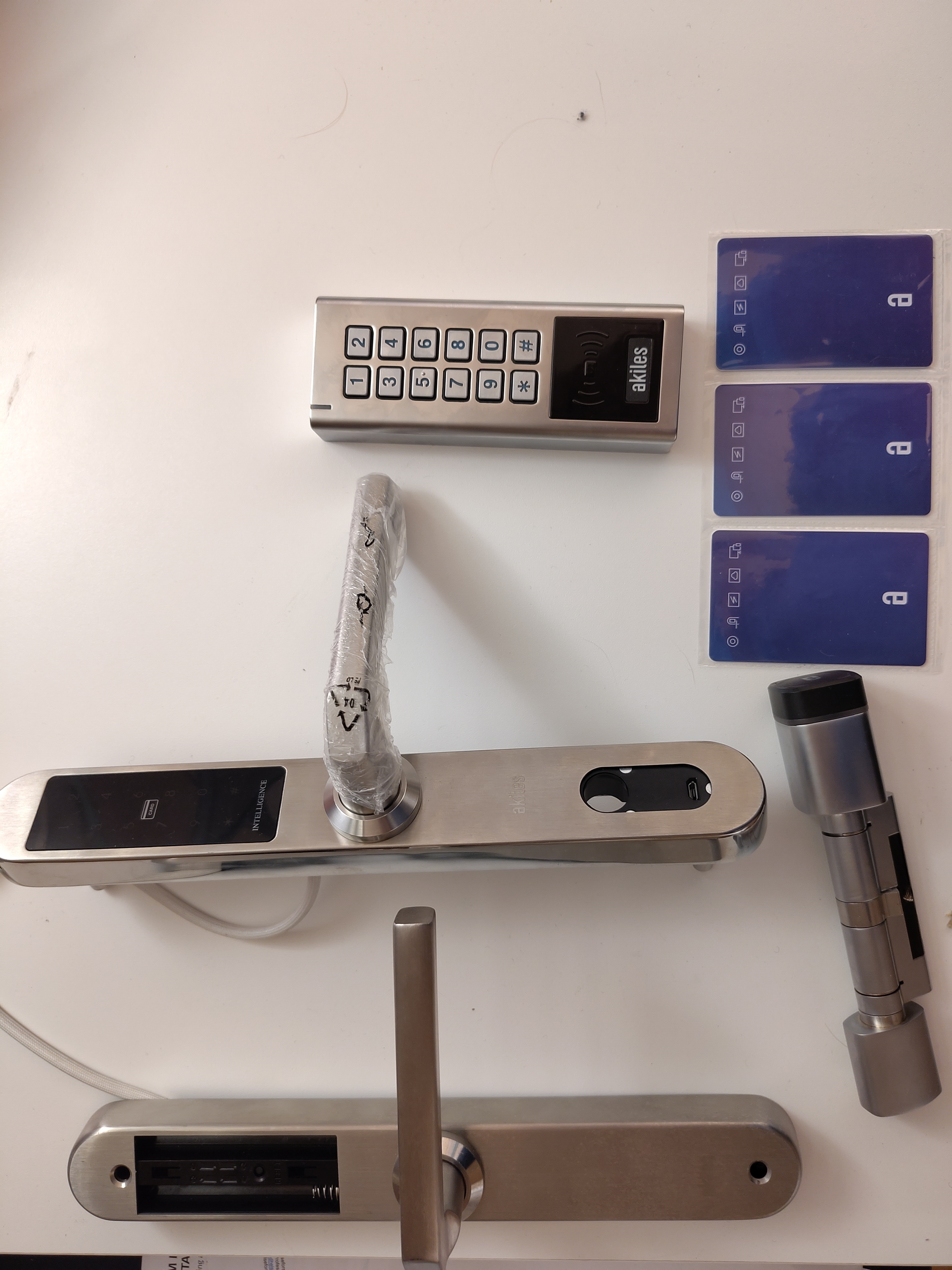 A photo showing the different Akiles products like cylinder lock, interior doorlock and some example access cards